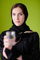 Image showing Woman in Abaya Holding a Date Fruit and glass of water