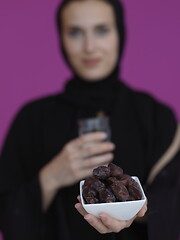 Image showing Woman in Abaya Holding a Date Fruit and glass of water