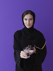 Image showing Woman in Abaya Holding a Date Fruit and glass of water