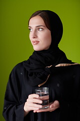 Image showing Woman in Abaya Holding a Date Fruit and glass of water