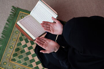 Image showing Middle eastern woman praying and reading the holy Quran