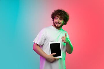 Image showing Caucasian young man\'s portrait on gradient studio background in neon