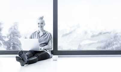 Image showing woman drinking coffee and using laptop at home