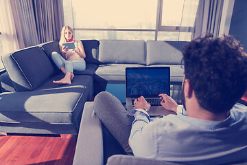 Image showing couple relaxing at  home using tablet and laptop computers