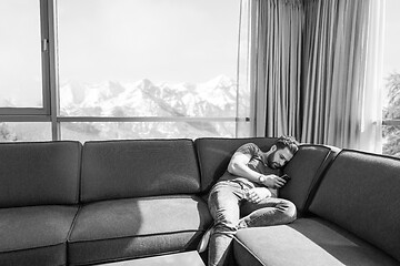 Image showing young casual man using a mobile phone at home