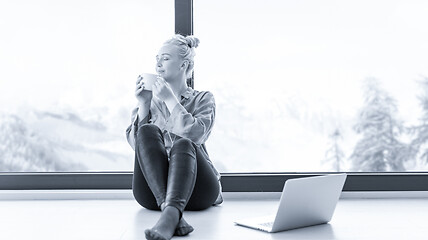 Image showing woman drinking coffee and using laptop at home