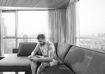 Image showing young casual man using a mobile phone at home