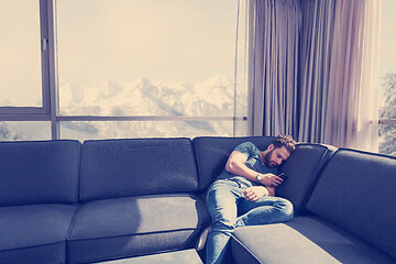 Image showing young casual man using a mobile phone at home