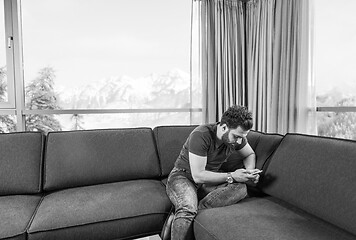 Image showing young casual man using a mobile phone at home