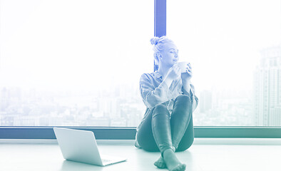 Image showing woman drinking coffee and using laptop at home