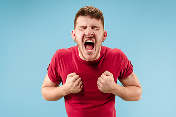 Image showing The young emotional angry man screaming on blue studio background