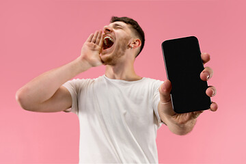 Image showing Young handsome man showing smartphone screen isolated on pink background in shock with a surprise face