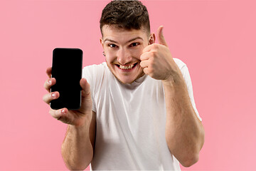 Image showing Young handsome man showing smartphone screen isolated on pink background in shock with a surprise face