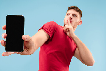 Image showing Portrait of the scared man with phone on blue