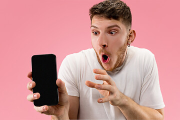 Image showing Young handsome man showing smartphone screen isolated on pink background in shock with a surprise face