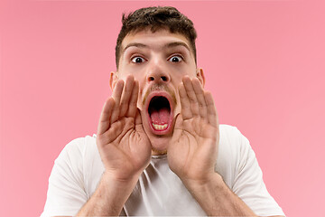 Image showing Isolated on pink young casual man shouting at studio