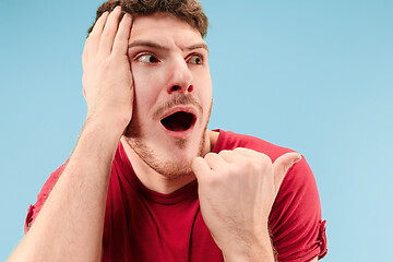 Image showing The young attractive man looking suprised isolated on blue