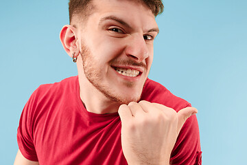 Image showing The young man whispering a secret behind her hand over blue background