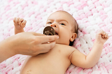 Image showing mother\'s hand giving pacifier to baby daughter