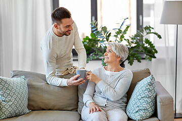 Image showing adult son bringing coffee to senior mother at home