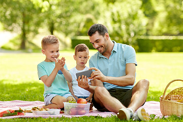 Image showing family with smartphone having picnic at park