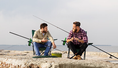 Image showing friends adjusting fishing rods with bait on pier