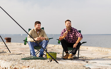 Image showing happy friends fishing and eating sandwiches