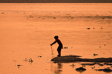 Image showing Asian Woman fishing in the river, silhouette at sunset