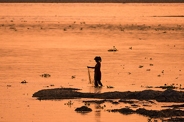 Image showing Asian Woman fishing in the river, silhouette at sunset