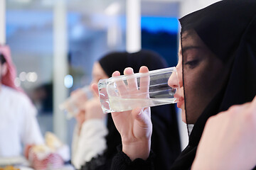 Image showing Muslim family having Iftar dinner drinking water to break feast