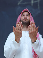 Image showing arabian man making traditional prayer to God, keeps hands in pra