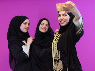 Image showing young muslim women taking selfie picture isolated on pink