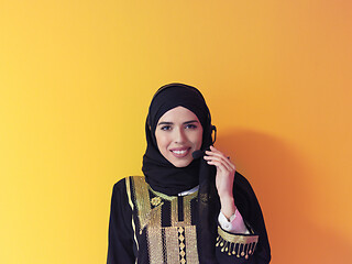 Image showing portrait of muslim woman with headset on yellow background