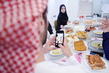 Image showing Muslim family having Iftar dinner taking pictures with mobile ph