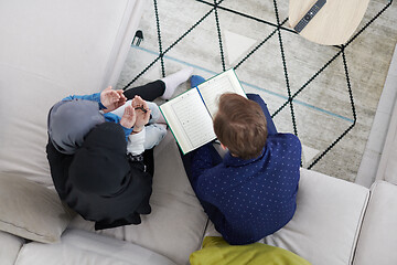 Image showing muslim family reading Quran and praying at home top view