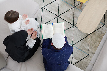 Image showing muslim family reading Quran and praying at home top view