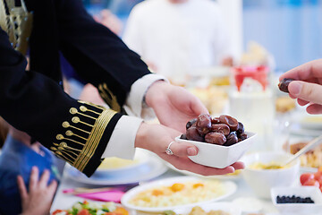 Image showing Muslim family having Iftar dinner eating dates to break feast