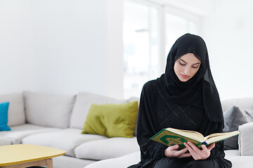 Image showing young muslim woman reading Quran at home