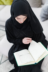 Image showing young muslim woman reading Quran at home