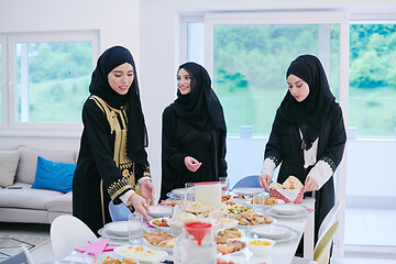 Image showing young muslim girls serving food on the table for iftar dinner