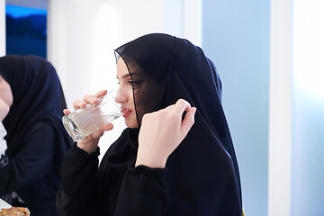 Image showing Muslim family having Iftar dinner drinking water to break feast