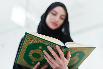 Image showing young muslim woman reading Quran at home