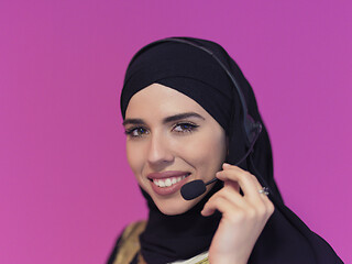 Image showing portrait of muslim woman with headset on pink background