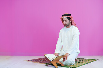 Image showing young arabian muslim man reading Quran at home