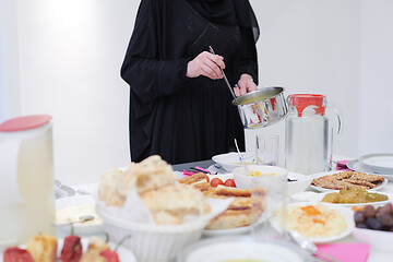 Image showing young muslim girl serving food on the table for iftar dinner