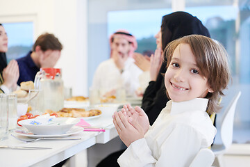 Image showing little muslim boy praying with family before iftar dinner