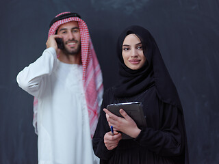 Image showing muslim couple using modern technology in front of black chalkboa