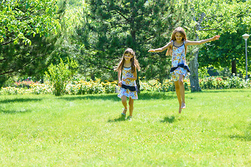 Image showing Two girls have fun running on the green lawn in the park