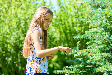 Image showing A girl stands by the spruce tree and looks thoughtfully and offended into the distance