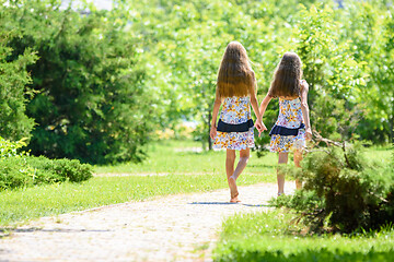 Image showing Two girls walk along a path in a beautiful city park